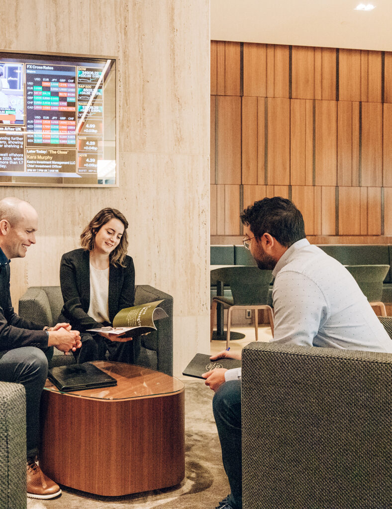 Three people sitting around a table in the Columbia Square building lobby